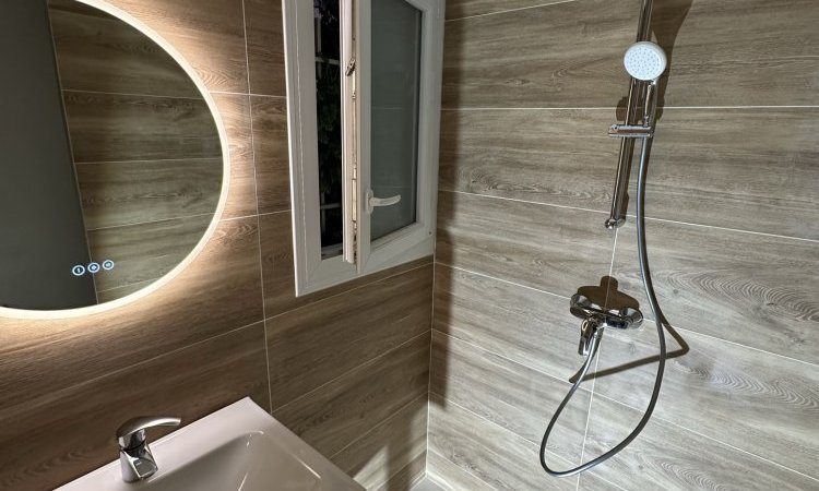 Rénovation salle de bain moderne avec cabine de douche en verre et mobilier en bois par Eau Secours